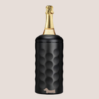 Customised sausage dog on a black textured wine cooler with a champagne bottle inside on a beige background 